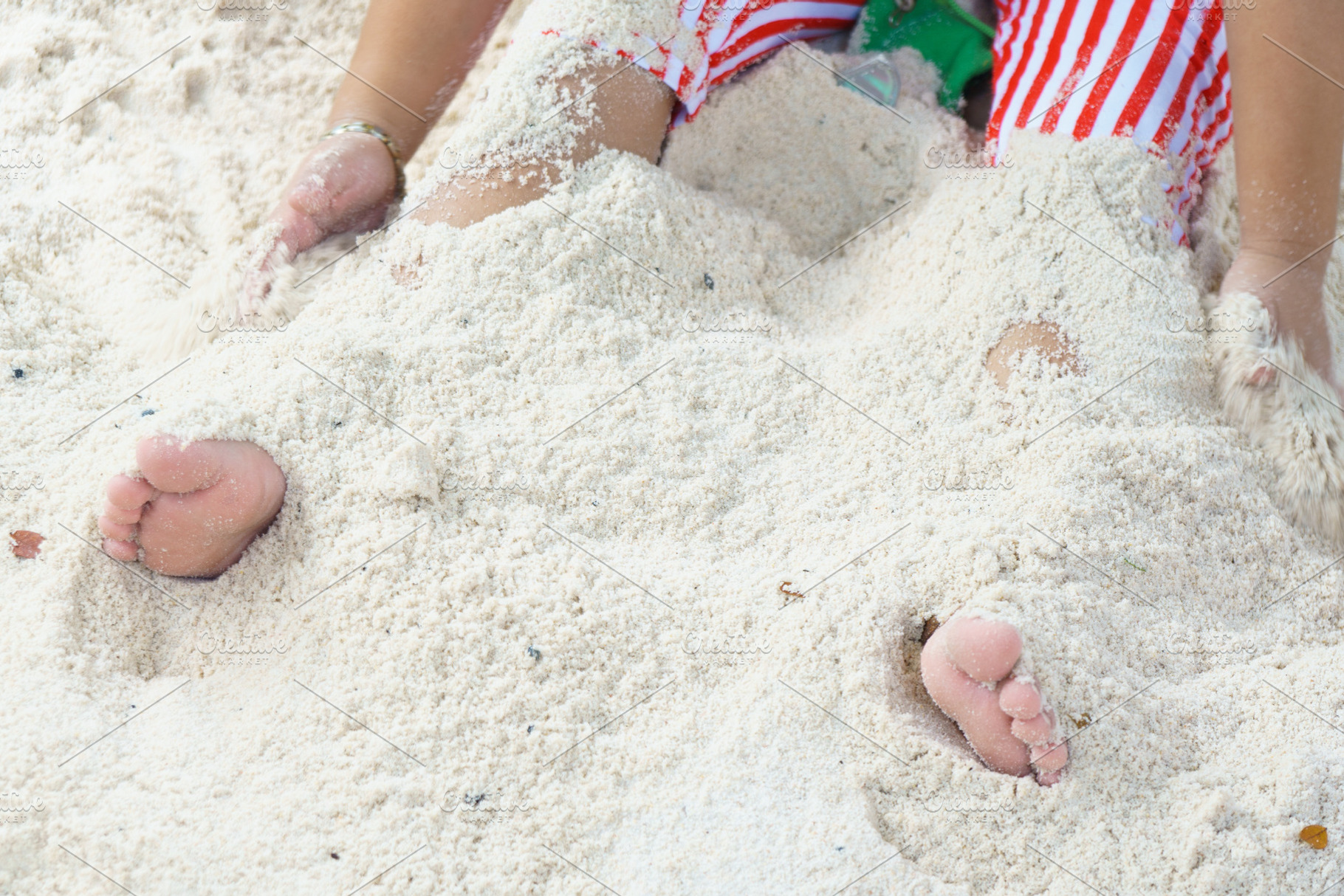 Buried feet in soft sand, playful beach scene with vibrant stripes, a Person Photo by a454