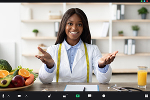 Cheerful african american nutritionist giving online consultations at workplace, a Person Photo by Prostock-Studio