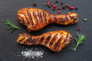 Grilled delicious chicken legs or chicken drumsticks on black s, a Food & Drink Photo by Volff