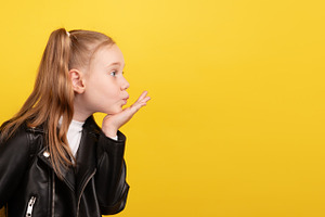 Side view of a young girl in a black leather jacket blowing a ki, a Person Photo by Ales Munt