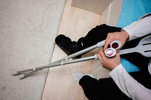 Injured person using crutches for support while seated indoors on a carpeted fl, a Health & Medical Photo by AS photostudio