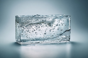 Ice block on reflective surface displaying intricate air bubbles and clear text, a Photo by Studio ANNA