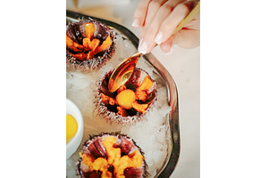 Woman having sea urchins at table, a Food & Drink Photo by Fascinadora