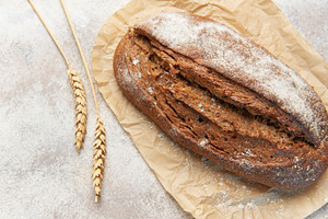 Rye bread loaf with wheat ears on parchment paper, a Food & Drink Photo by Olena Rudo
