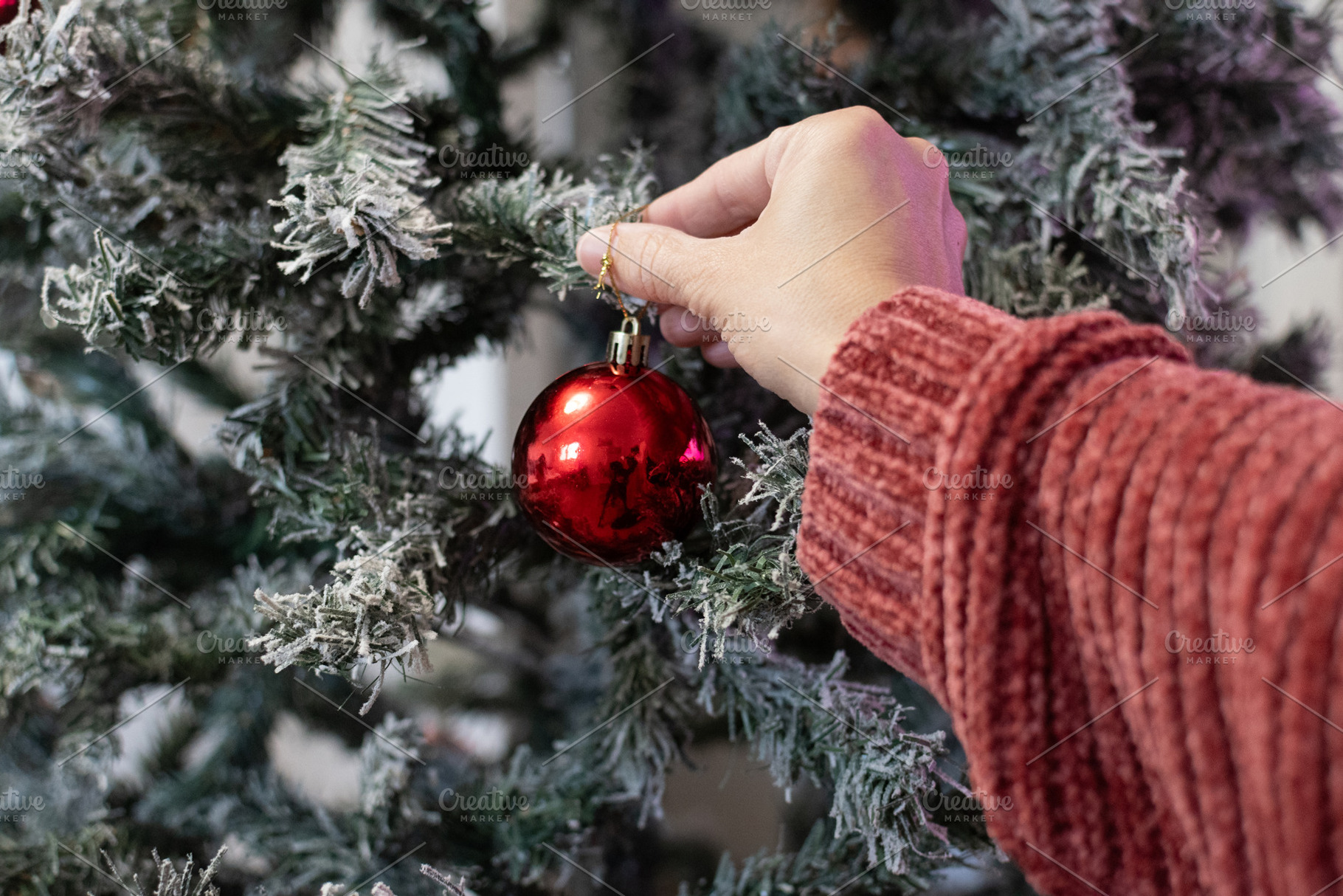 Woman hand placing ornament on Christmas tree, a Food & Drink Photo by etorres69