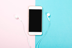 Smartphone and headphones on pink and blue background technology containing