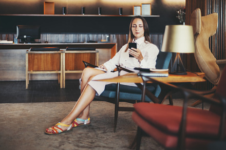 Woman in hotel reception using phone, a Person Photo by SkyNext