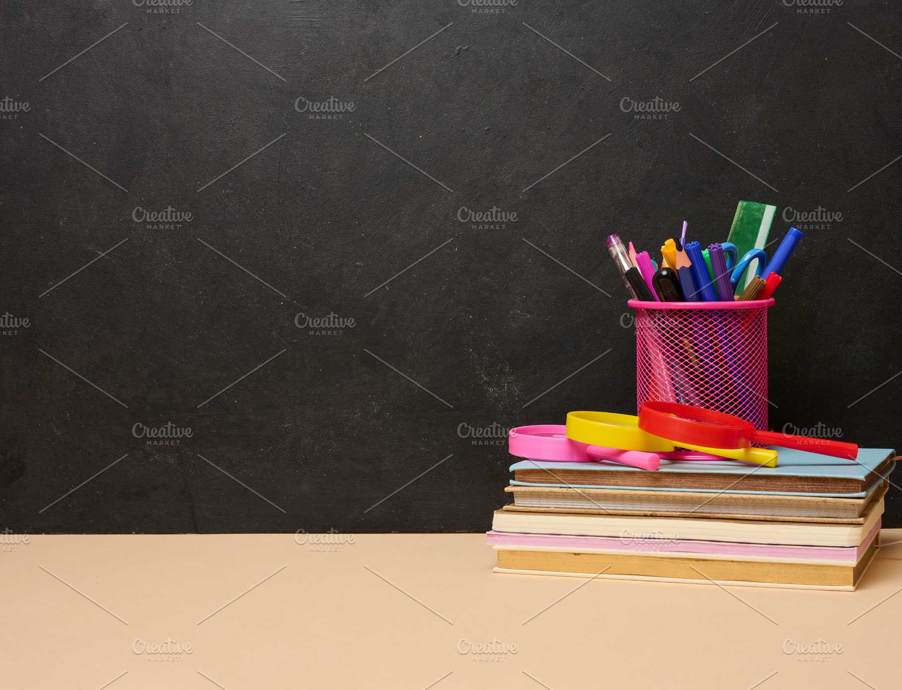 A stack of colorful books, a pink glass with pens and pencils, a, a School & Education Photo by ndanko