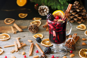 Glass of hot mulled wine for the new year with ingredients for cooking nuts