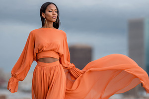 Influencer woman showcases stylish outfit against urban skyline backdrop, a Person Photo by OSORIOartist