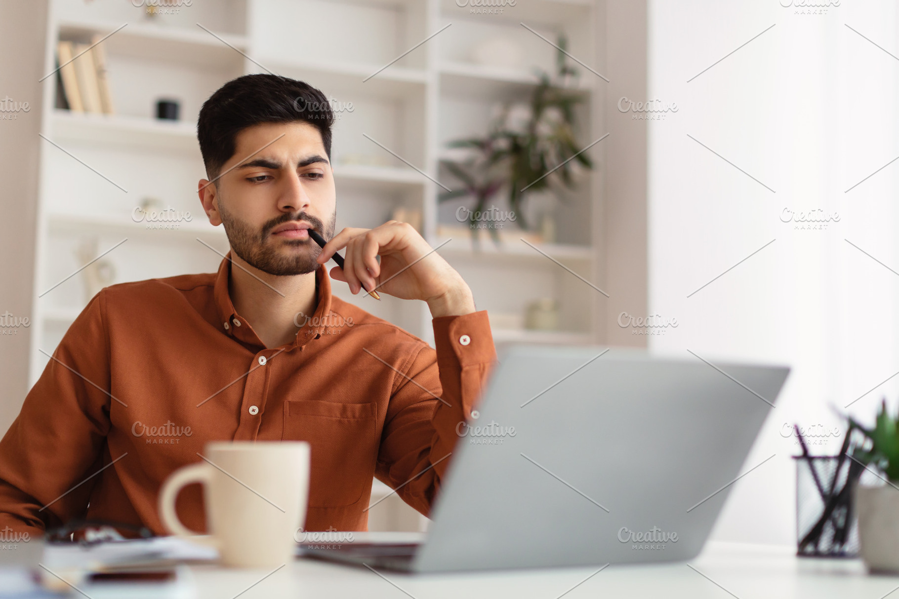Arab man using laptop sitting at desk in office, a Photo by Prostock-Studio