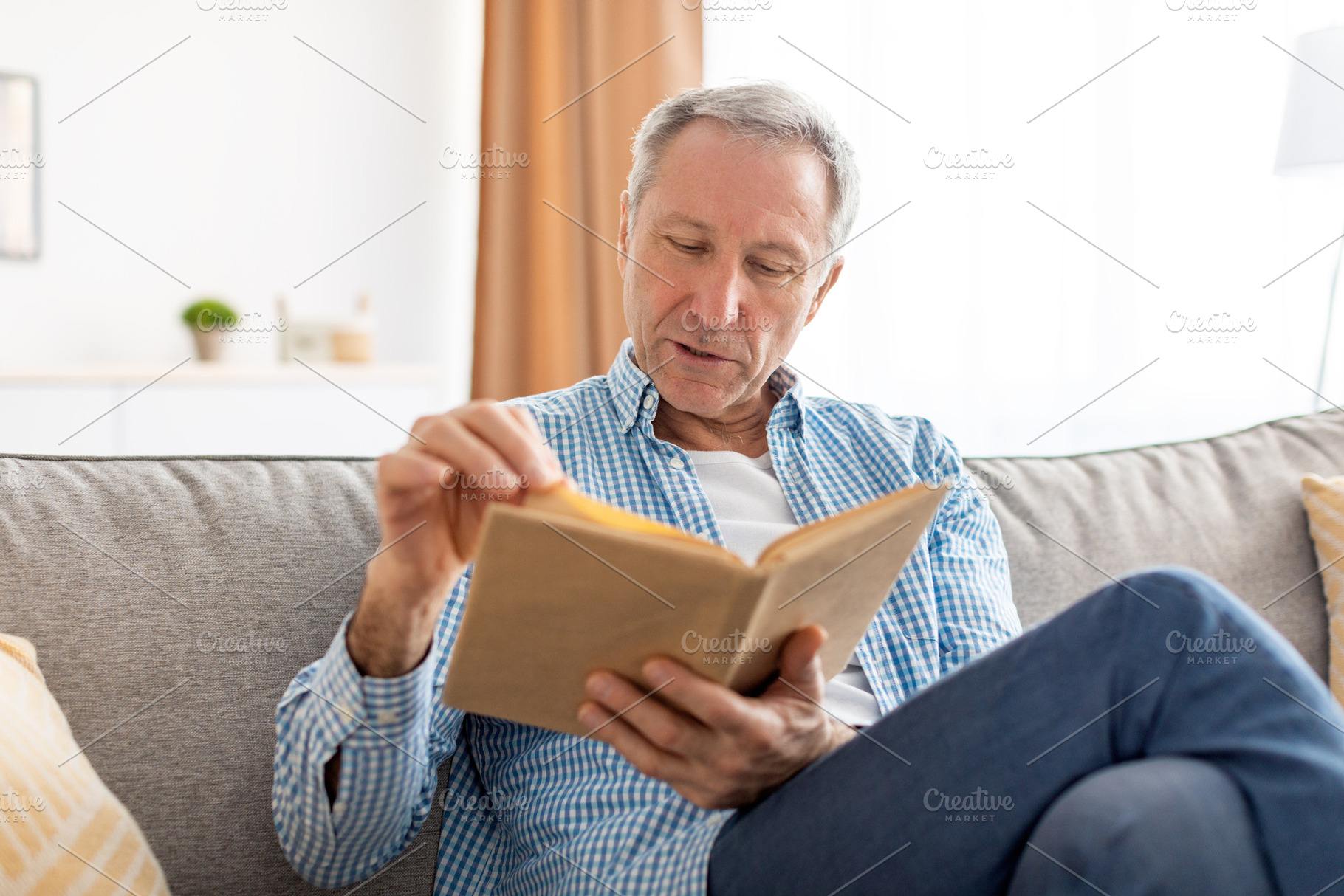 Portrait of mature man reading book at home, a Photo by Prostock-Studio