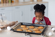 Emotional little black girl looking at fresh homemade cookies, a Photo by Prostock-Studio (Thumbnail 2 of 2)