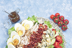 Delicious Cobb salad on a white plate, vertical top view copy space, a Food & Drink Photo by iuliia_n