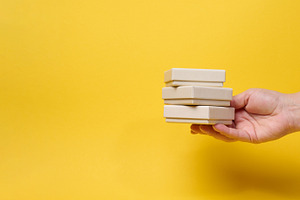 A woman's hand holds a stack of three small gift boxes on a brig, a Holiday Photo by ndanko