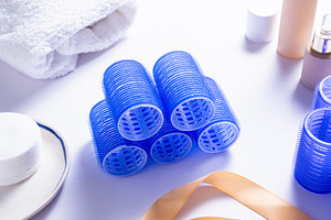 Set of Blue Plastic Hair Rollers with Hair Care Products on Whit, an Industrial Photo by MDBildes