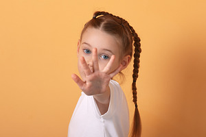 Portrait of a young girl with braids playfully extending her han, a Person Photo by Ales Munt