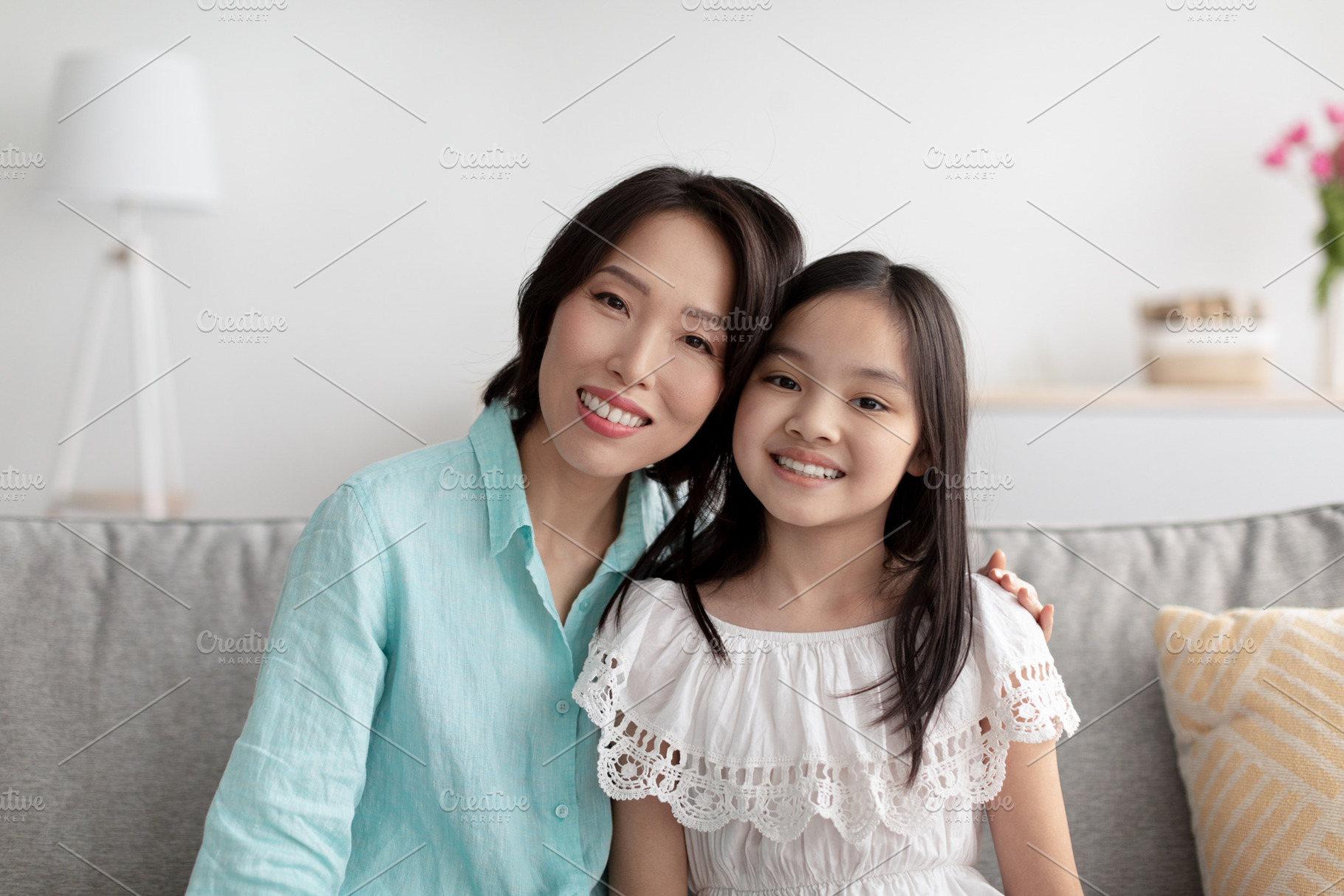 Portrait of cheerful mature Asian woman and her adorable granddaughter sitting, a Photo by Prostock-Studio