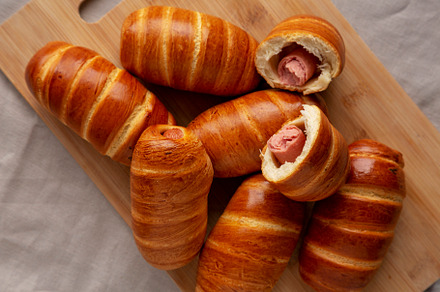 Homemade Sausage Buns on a bamboo board, top view. Flat lay, ove, a Food & Drink Photo by LiudmylaChuhunova
