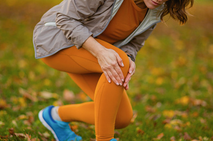 sad modern woman in fitness clothes in park got leg injury, a Sports & Recreation Photo by Alliance Images