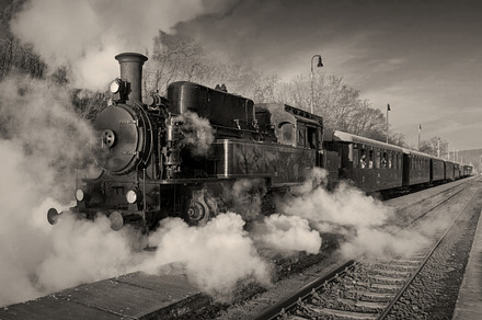 Historic steam train containing locomotive, smoke, and historical