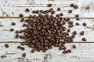 Heap of coffee beans on wooden table, a Food & Drink Photo by AlyaAnd