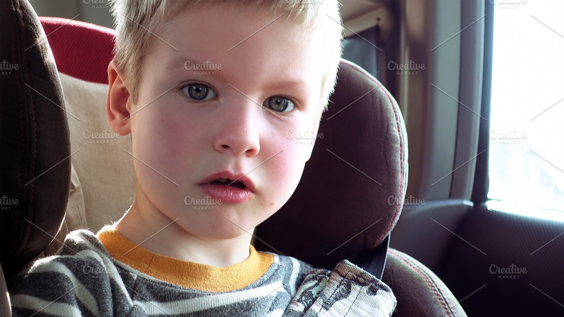 Cute boy in a child car seat containing boy, child, and look out the window, a Person Photo by HighRes Pictures