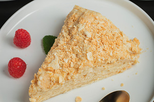 Sliced Napoleon cake on a white wooden table. Classic dessert, a Food & Drink Photo by Budarinphoto