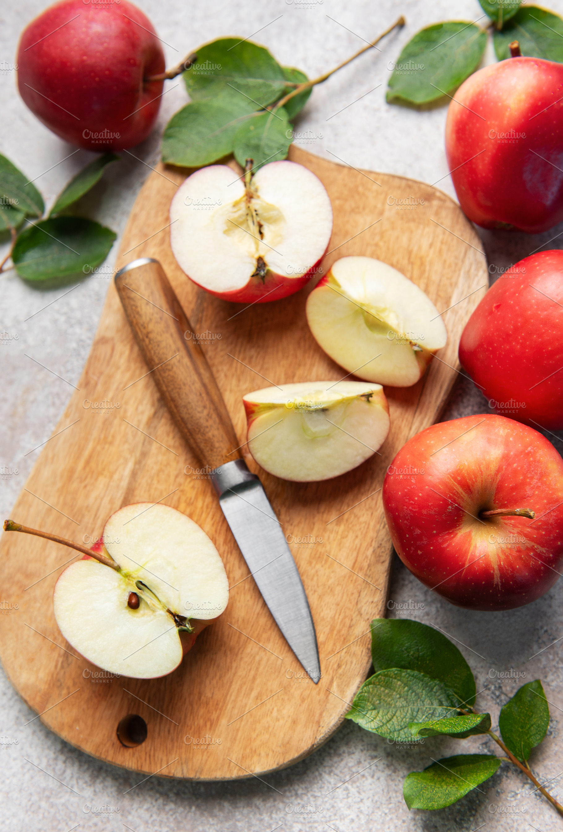Fresh red apples and slices with knife on wooden cutting board, a Food & Drink Photo by Olena Rudo