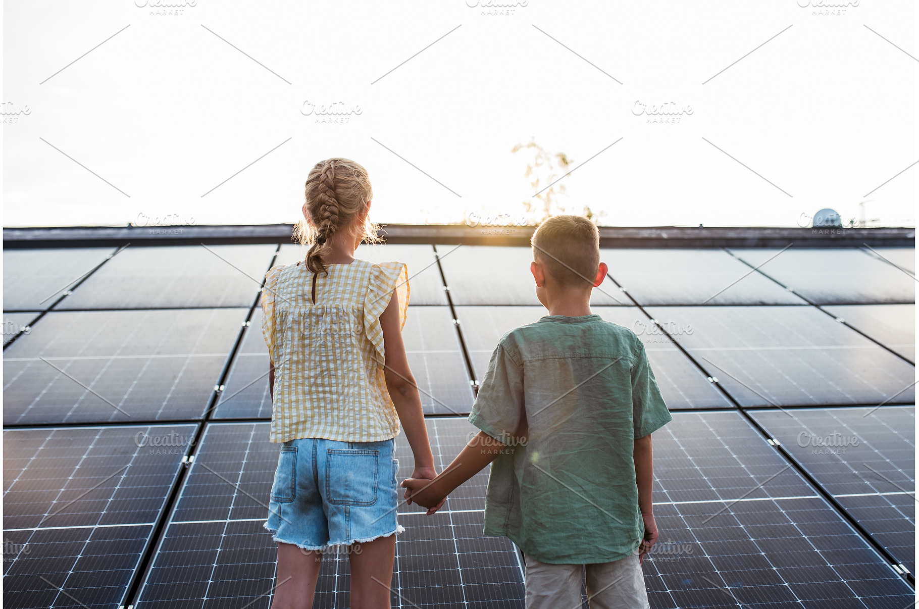 Siblings on roof with solar panels, a Technology Photo by HalfPoint
