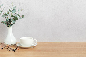 Eucalyptus branches, coffee cup and eyeglasses resting on wooden, a Background Photo by Olena Rudo