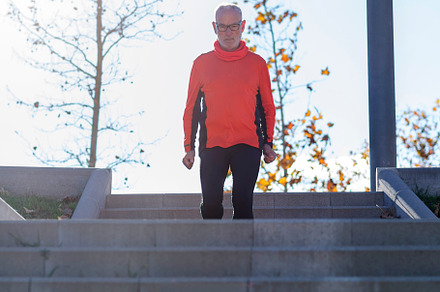 Senior man walking down stairs in a sunny outdoor park