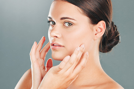 Woman, portrait and face in beauty for skincare, makeup or cosmetics isolated against a gray studio background. Beautiful female touching smooth, soft or perfect skin in satisfaction for treatment, a Photo by Peopleimages.com