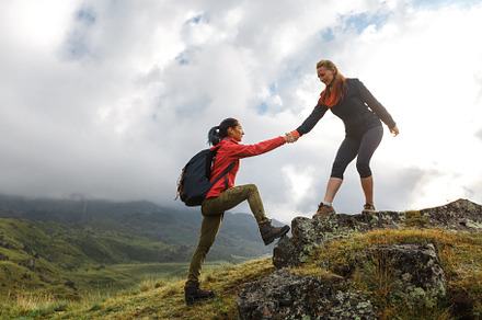 Girls helping each other hike up a m
