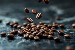 Coffee beans falling on a dark stone, a Photo by Volff
