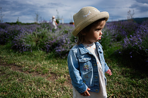 Young girl walking in a lavender field wearing denim jacket and straw hat, a Photo by AS photostudio