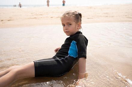 Little girl surfer in wetsuit lies ocean beach, a Person Photo by andreonegin market