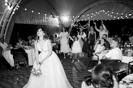 bride in a white dress throws a wedding bouquet