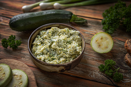Bowl of zucchini spread is surrounded by fresh zucchini slices,, a Photo by Grafvision photography