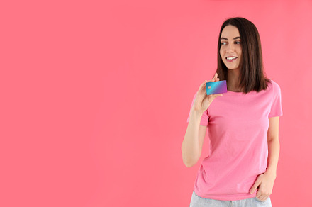 Attractive woman in t-shirt holds card on pink background, a Person Photo by AtlasStudio PRO