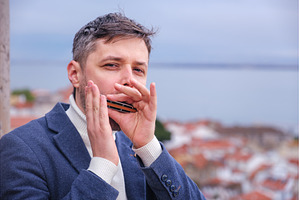 Man plays harmonica outdoors in city