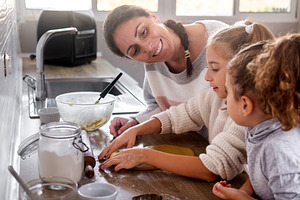 Mother and daughters mixing ingredients for Christmas cookies in kitchen, a Person Photo by etorres69