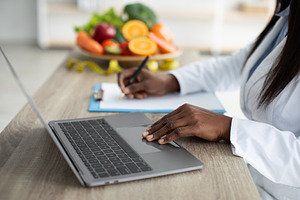 Working process. African american dietitian creating diet plan for patient or c, a Person Photo by Prostock-Studio