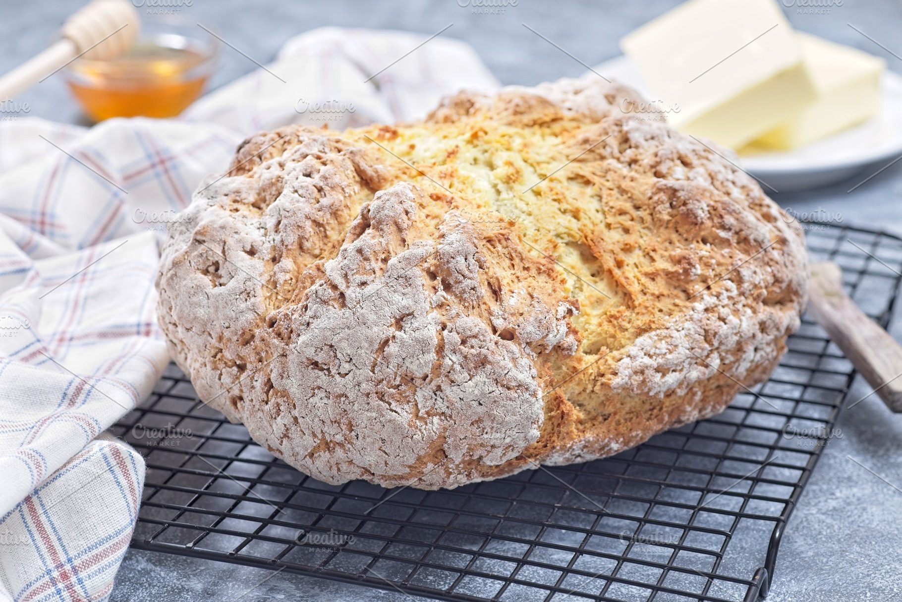 Freshly baked soda bread on cooling rack with butter and honey in the backgroun, a Food & Drink Photo by iuliia_n