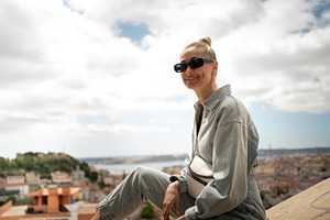 Happy woman sitting on retaining wall at Senhora do Monte viewpoint, a Person Photo by andreonegin market