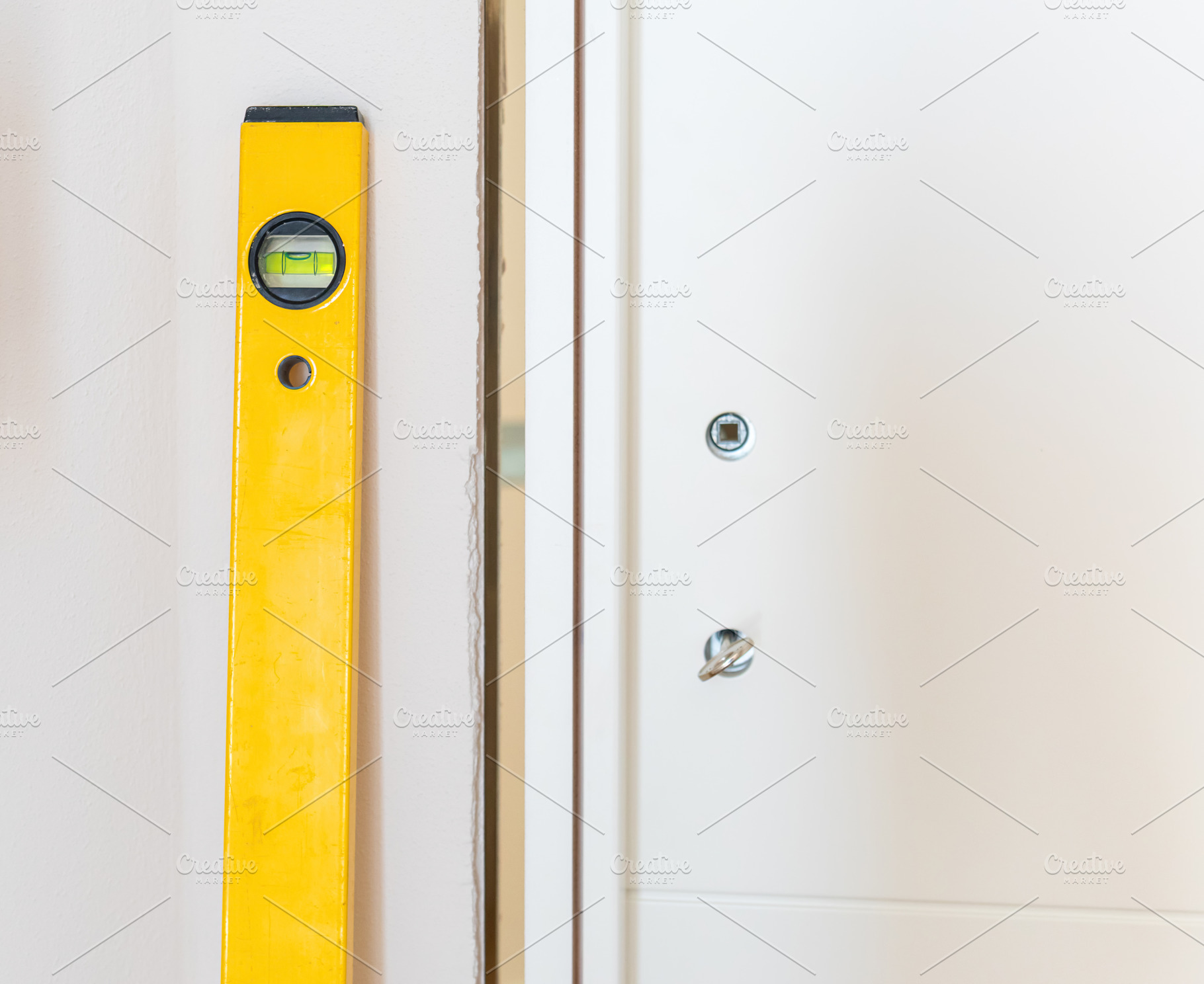 Construction worker using spirit level installing white door in a house, an Architecture Photo by Antonio Gravante Market