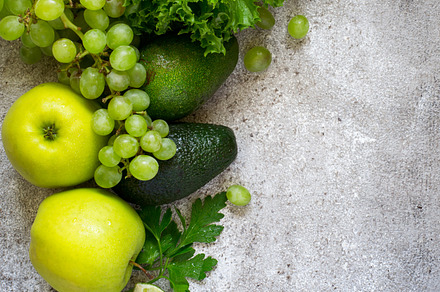 Selection of green vegetables and fruits on a gray concrete back containing, a Health & Medical Photo by colnihko
