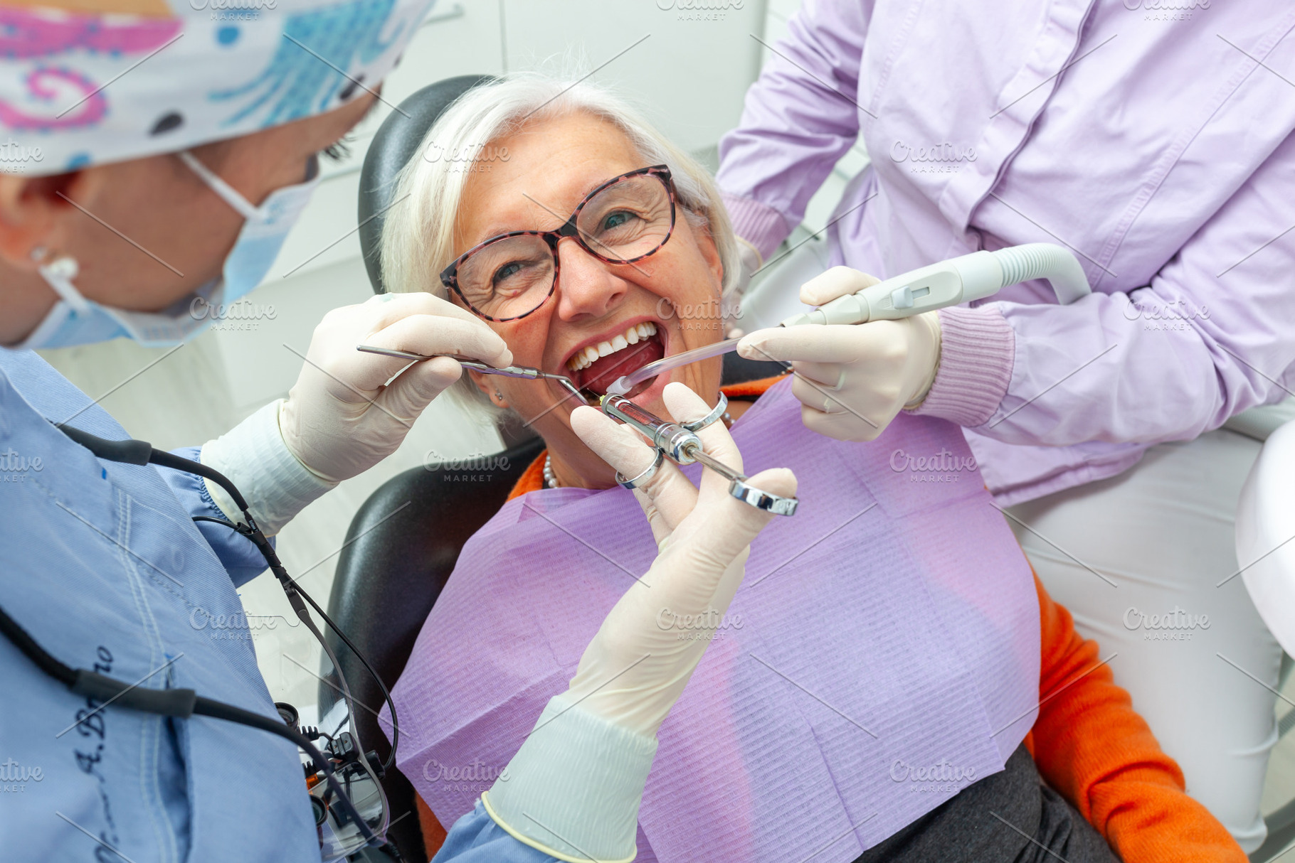 Dentists performing dental procedure on senior woman in clinic, a Health & Medical Photo by Antonio Gravante Market