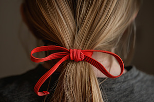 Woman tying her hair using band. Back view, a Beauty & Fashion Photo by AlyaAnd