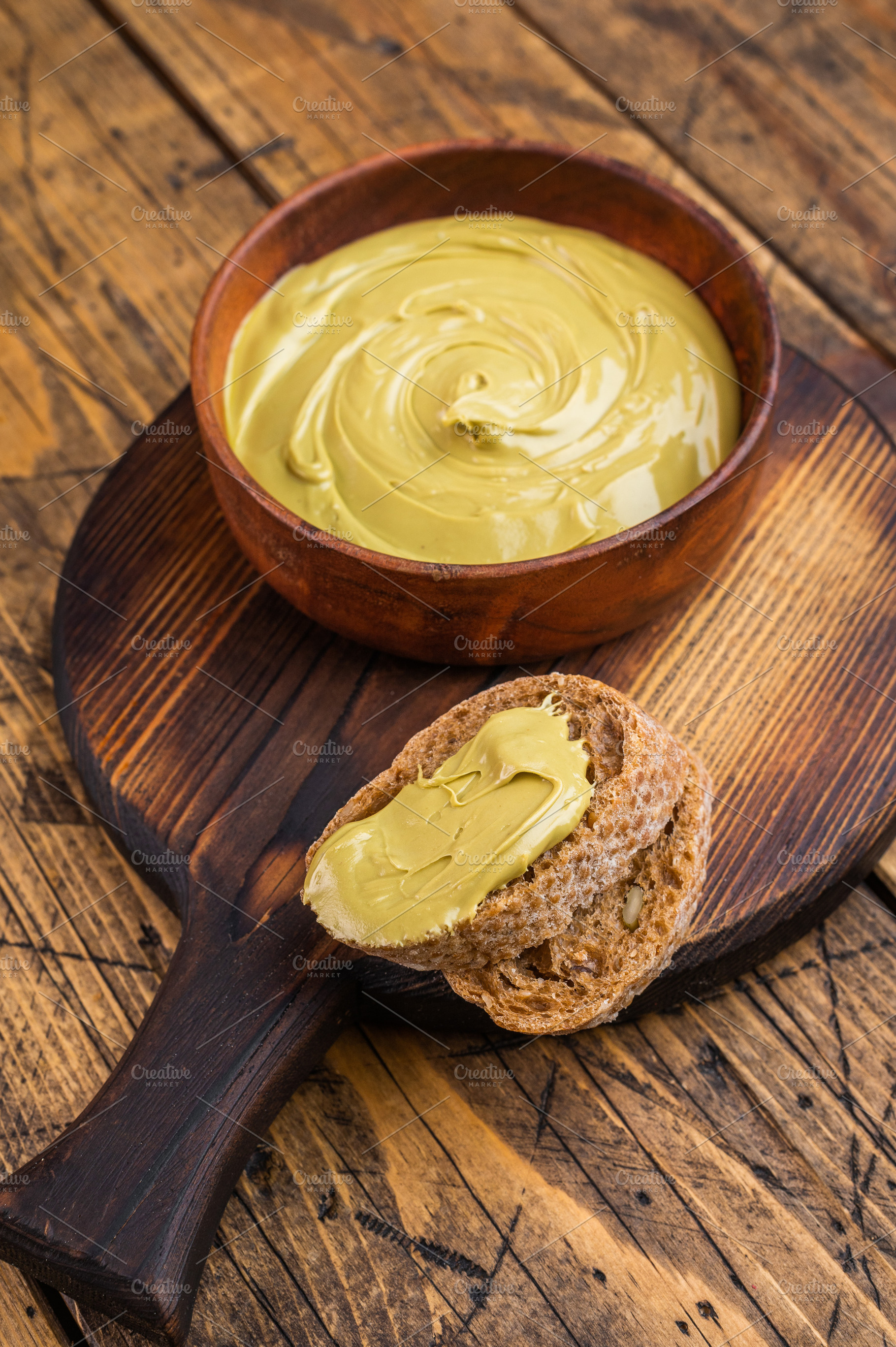 Sweet pistachio cream spread on bread with wooden bowl and knife, a Food & Drink Photo by composter-box@mail.ru